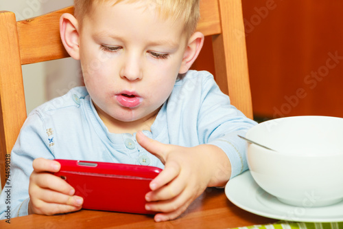 Fotografi boy drooling eating breakfast playing with mobile phone