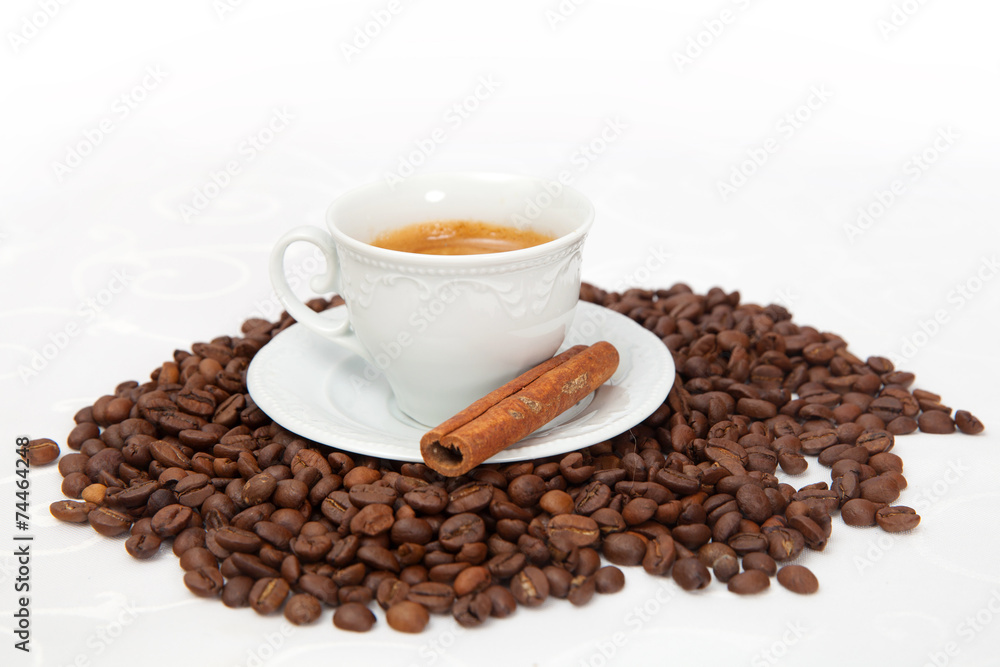 The cup of black coffee with grains and cinnamon stick The cup of black coffee with grains and cinnamon stick
