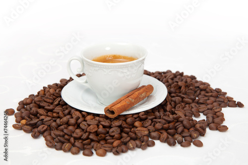 The cup of black coffee with grains and cinnamon stick