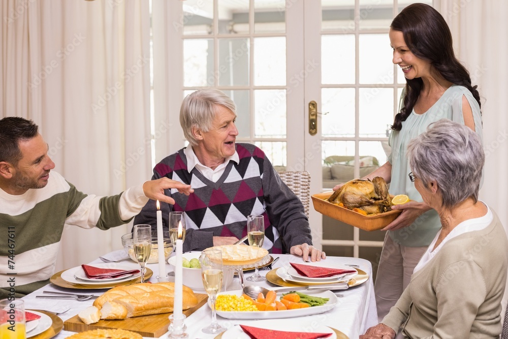 Woman holding turkey roast with family at christmas Woman holding turkey roast with family at christmas