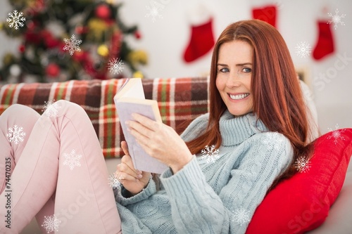 Composite image of festive redhead reading on the couch