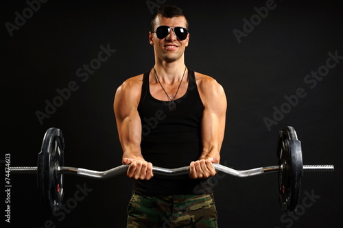 Young man in sunglasses exercises with dumbbells