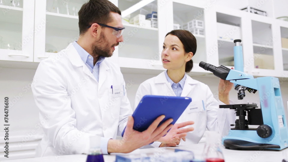 scientists with tablet pc and microscope in lab scientists with tablet pc and microscope in lab