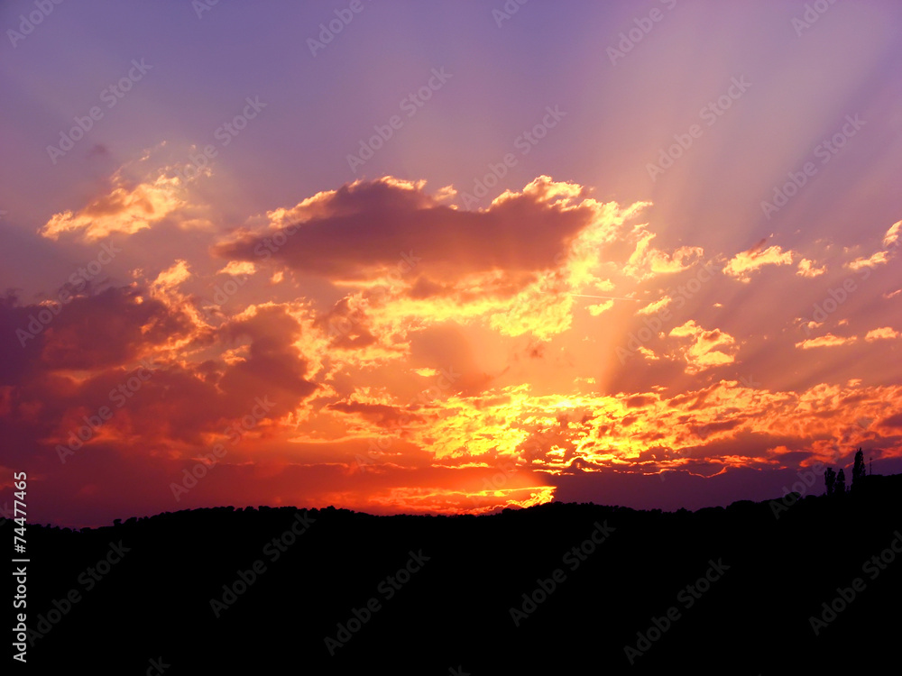 Vibrant and colorful purple sunset with silhouette of mountain