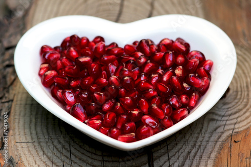 Pomegranate seeds on a plate in the form of heart