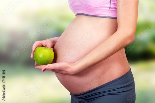 Abdomen of pregnant women and green apple.