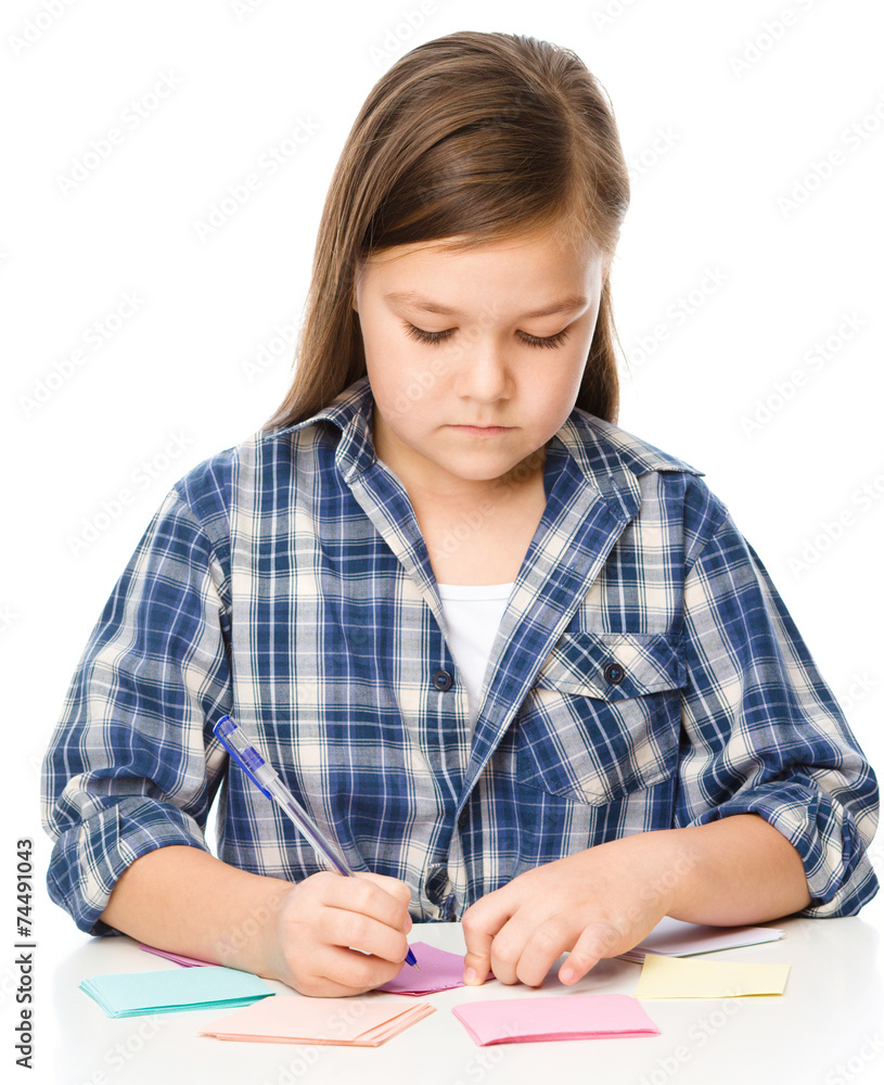 Girl is writing on color stickers using pen Girl is writing on color stickers using pen