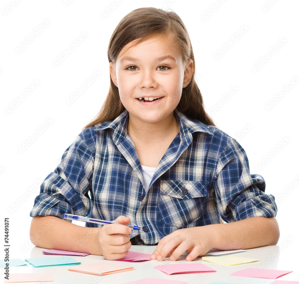 Girl is writing on color stickers using pen Girl is writing on color stickers using pen