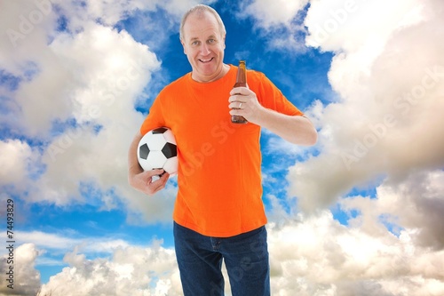 Mature man in orange tshirt holding football and beer