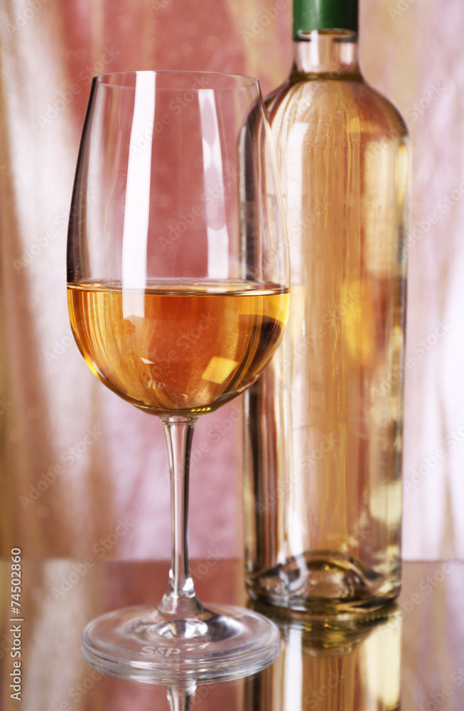 Wine bottle and wineglass with white wine on bright background