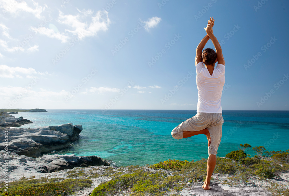 young man making yoga exercises outdoors