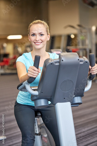 smiling woman exercising on exercise bike in gym