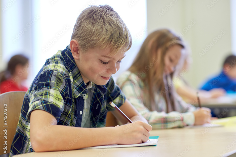 group of school kids writing test in classroom group of school kids writing test in classroom