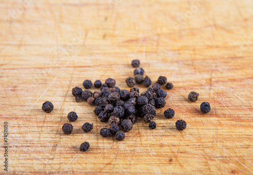 Black pepper seeds on a wooden board
