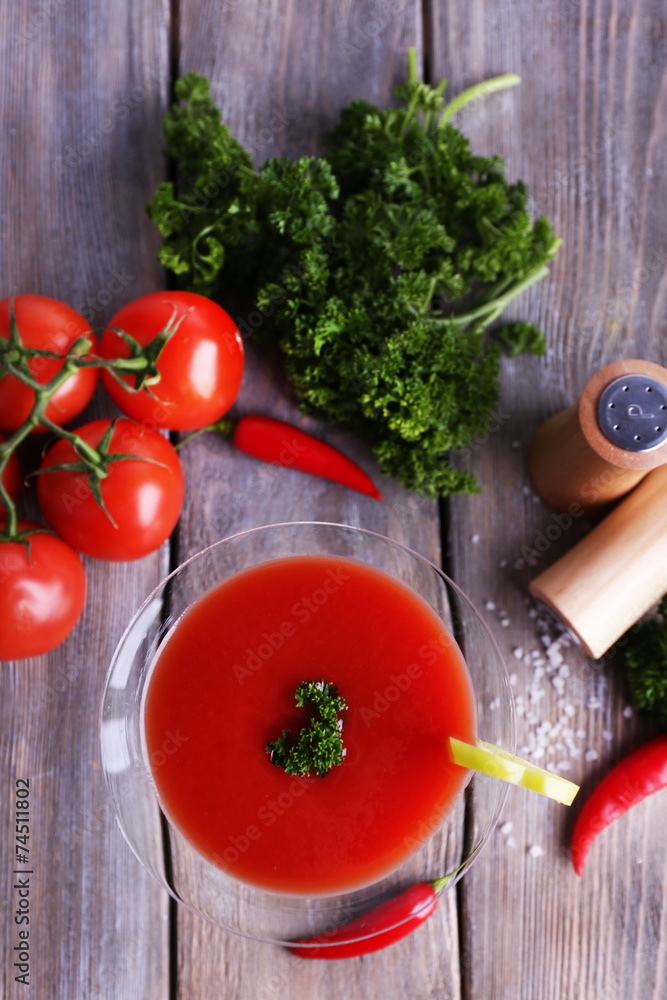 Tomato juice in goblet and fresh vegetables on wooden Tomato juice in goblet and fresh vegetables on wooden