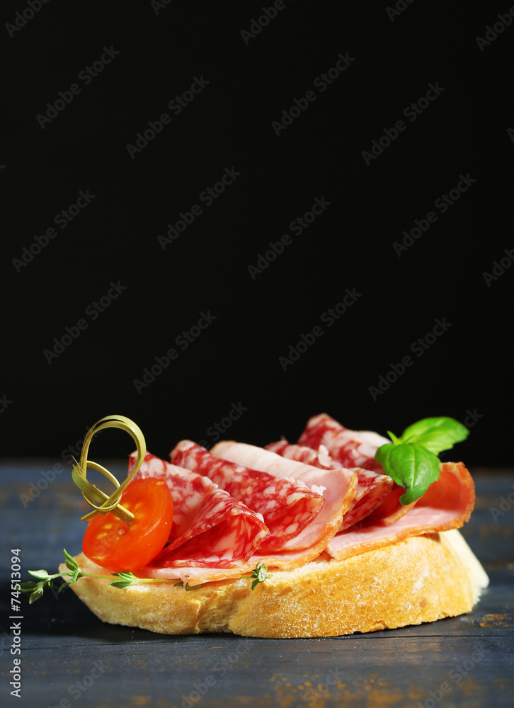 Tasty sandwich on wooden table, on black background Tasty sandwich on wooden table, on black background