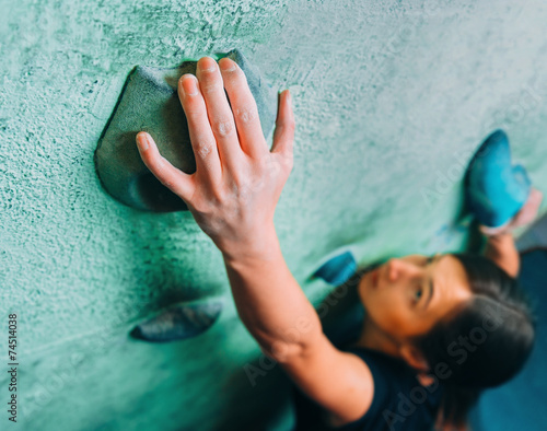 Woman climbing up on wall in gym photo