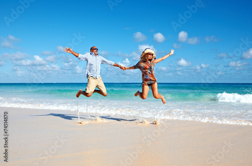 Happy couple jumping on the beach.