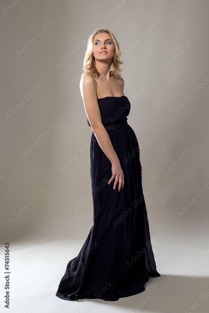 Smiling pretty blonde posing in long black dress Smiling pretty blonde posing in long black dress