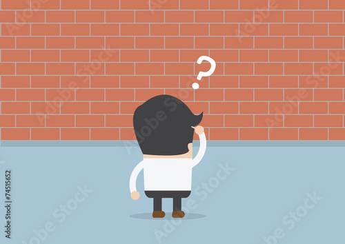 Businessman standing in front of a large brick wall