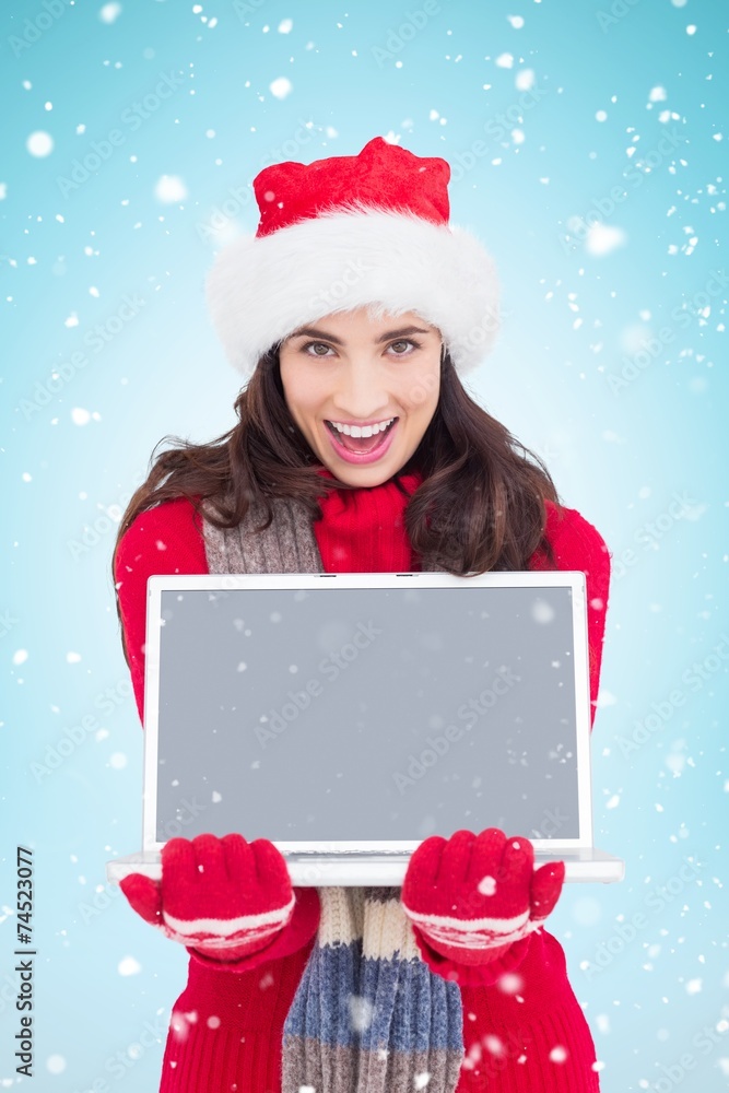 Composite image of festive brunette showing a laptop Composite image of festive brunette showing a laptop