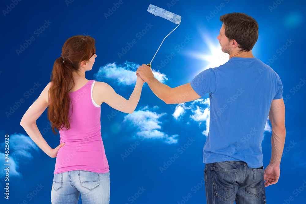 Composite image of couple painting a wall together Composite image of couple painting a wall together