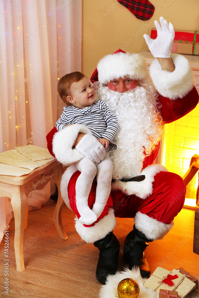 Obraz premium Santa Claus holding little cute girl near fireplace and