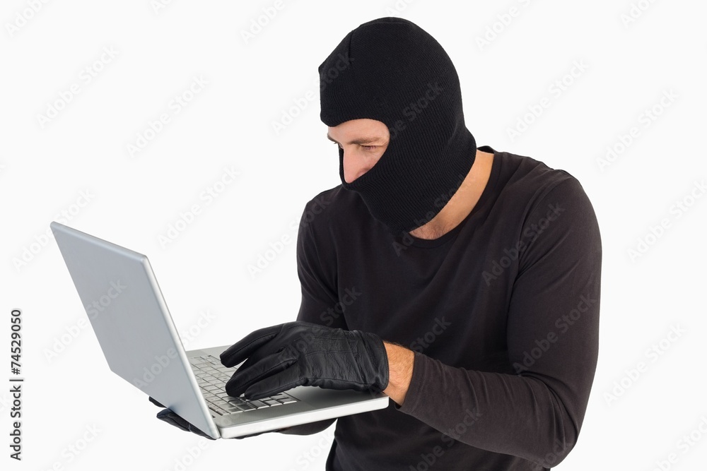 Focused burglar standing holding laptop Focused burglar standing holding laptop