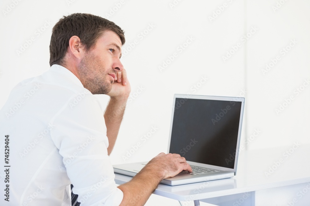 Thinking businessman sitting at desk using laptop Thinking businessman sitting at desk using laptop