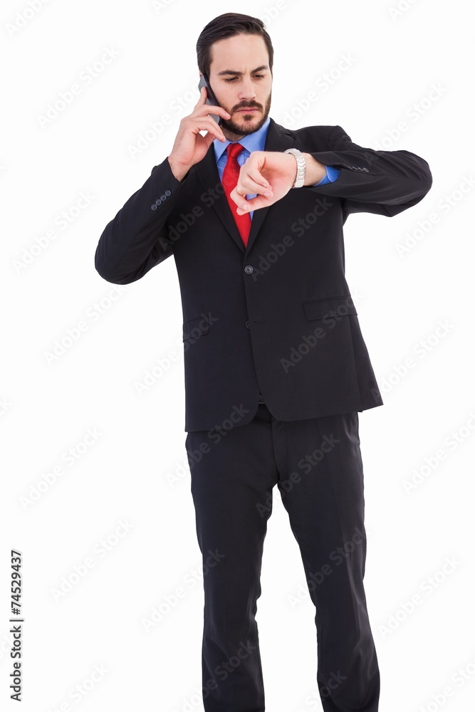 Serious businessman checking the time while on the phone Serious businessman checking the time while on the phone