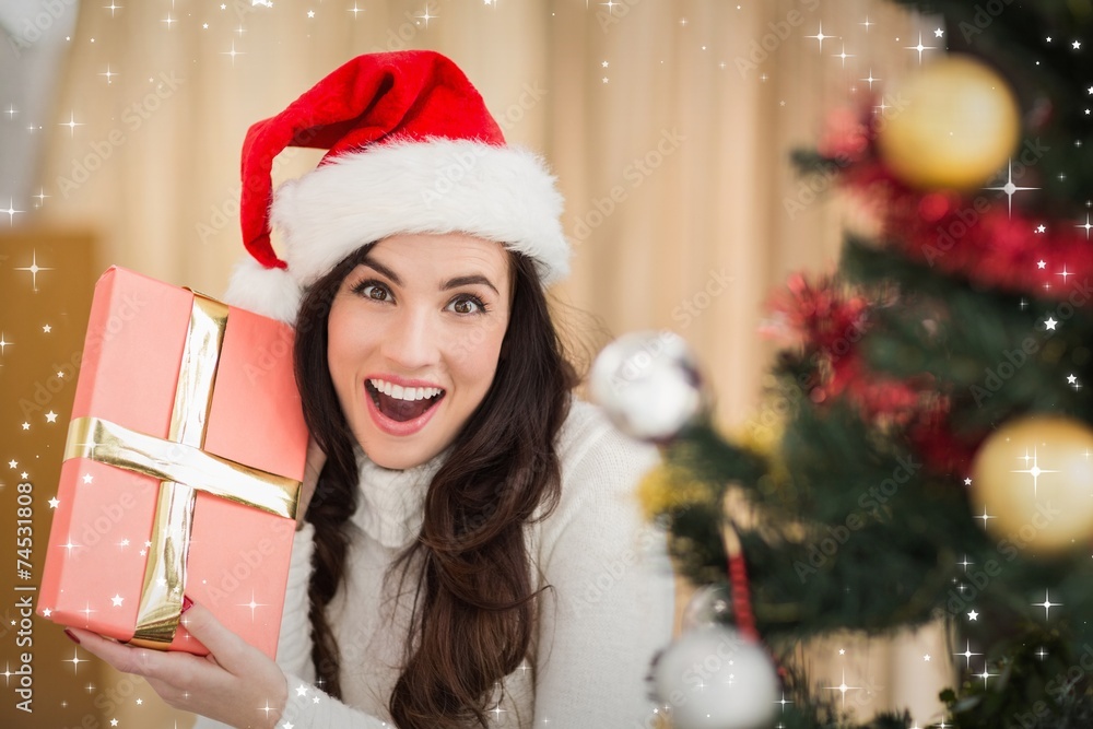 Composite image of surprised brunette holding a gift Composite image of surprised brunette holding a gift
