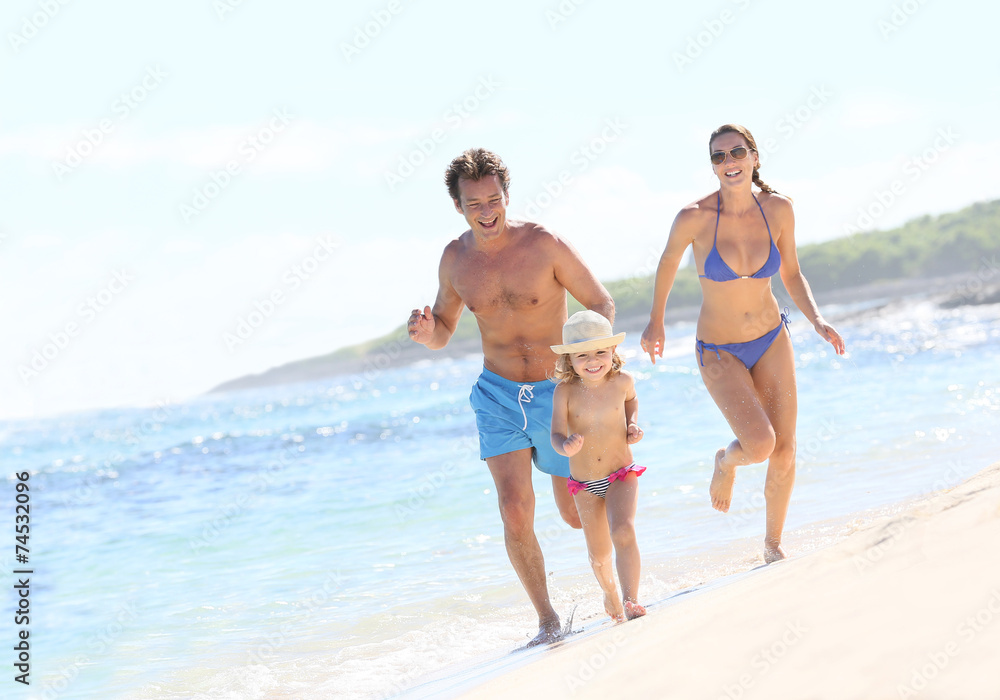 Family running in swimsuit on a Caribbean beach