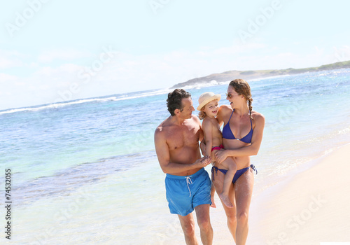 Happy family walking on the beach in summer