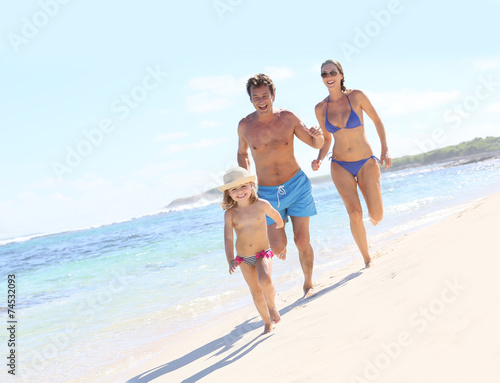 Family running in swimsuit on a Caribbean beach © goodluz