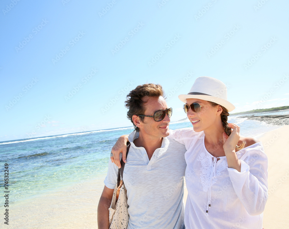 Trendy couple walking on a sandy beach
