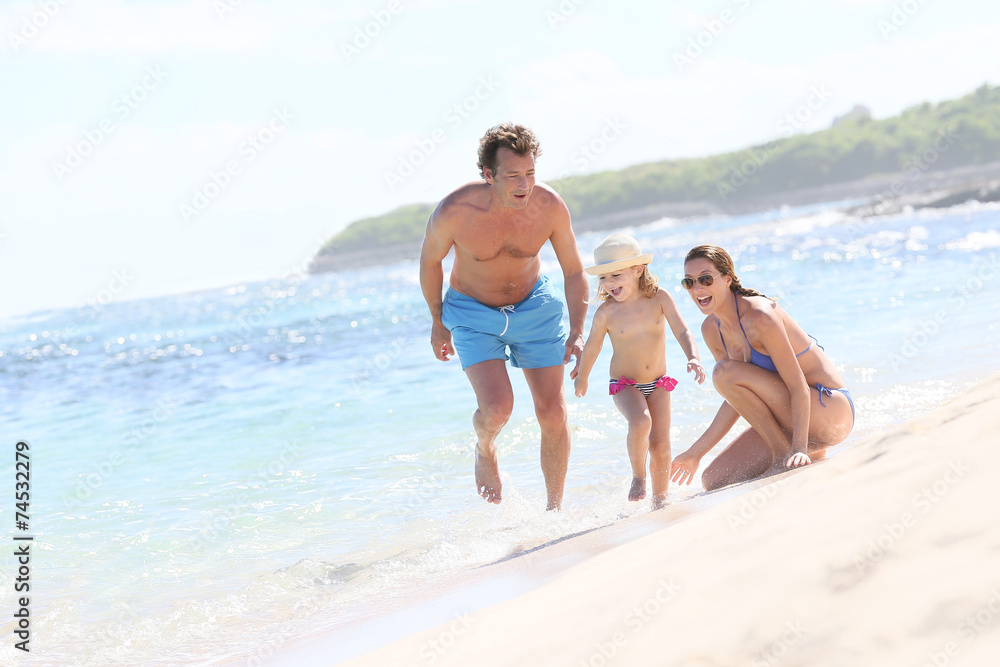 Family of three playing on a sandy beach in summertime