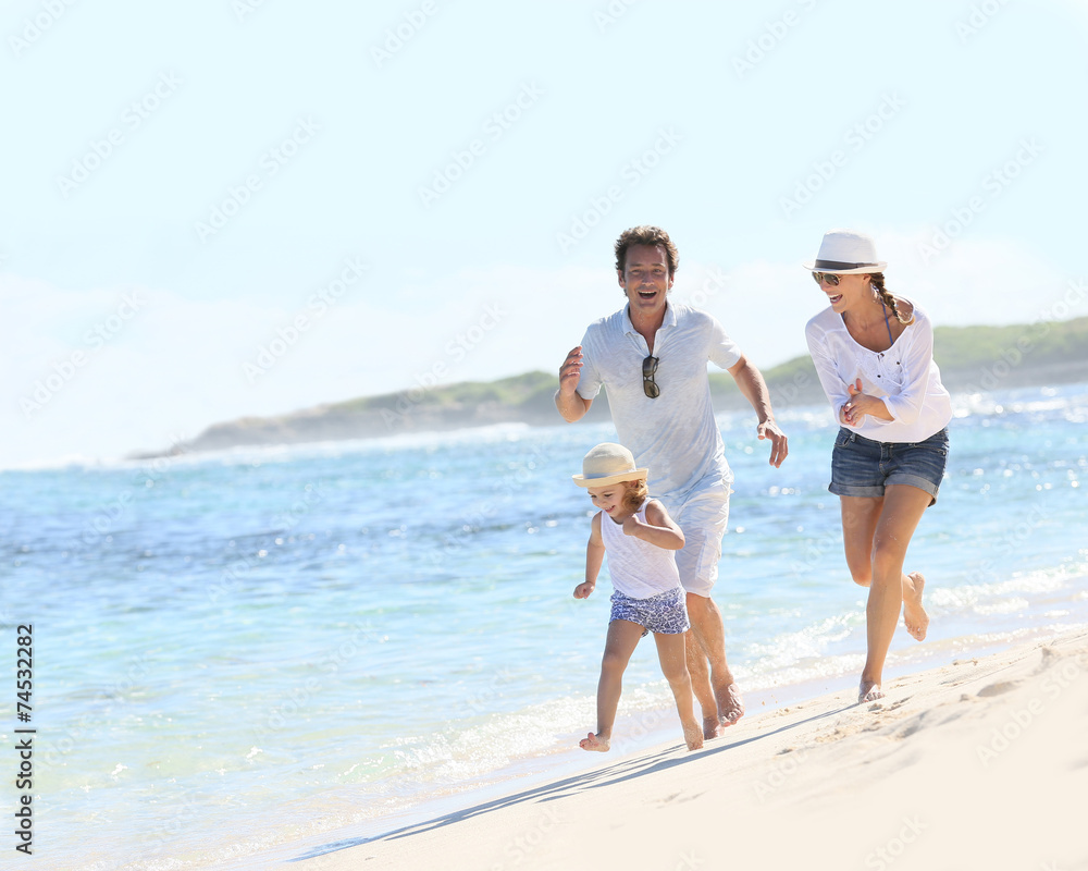 Couple with little girl running on Caribbean beach