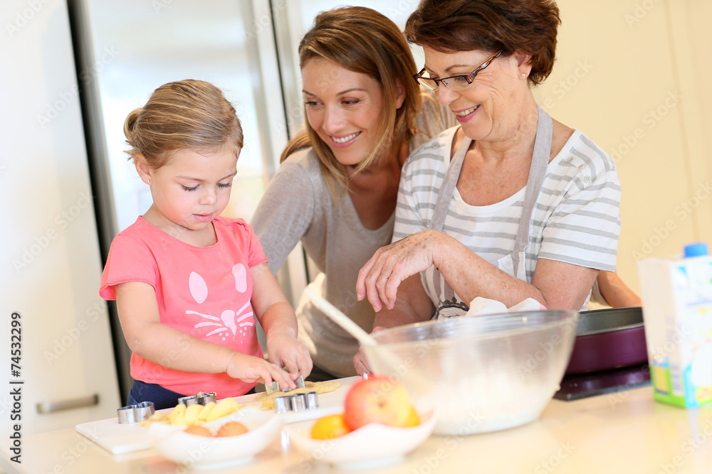 Little girl with mom and grandmother baking cookies at home Little girl with mom and grandmother baking cookies at home