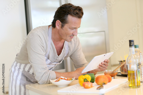 Handsome man in kitchen looking at digital tablet for recipe
