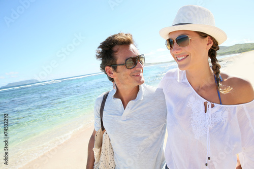 Trendy couple walking on a sandy beach © goodluz