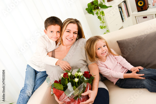 young happy childrens offering flowers to mum for mother's day