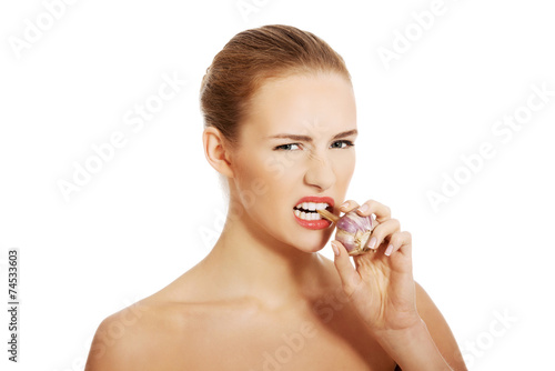 Portrait of nude woman eating garlic