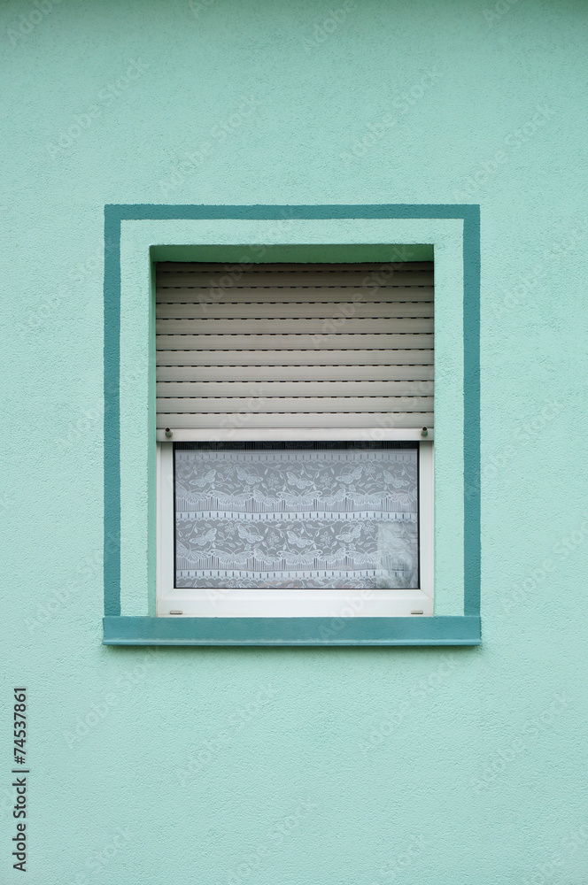 Einfaches PVC Fenster mit Rollladen in grüner Fassade