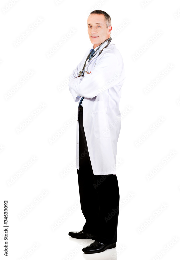 Side view full length male doctor with folded arms Side view full length male doctor with folded arms