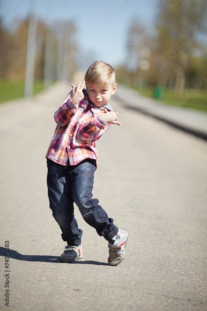 Fototapeta premium little boy grimacing on the street in april