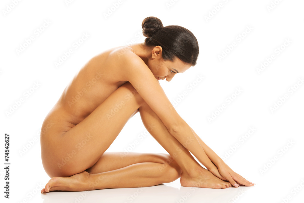 Fototapeta premium Side view of naked woman sitting touching her foot