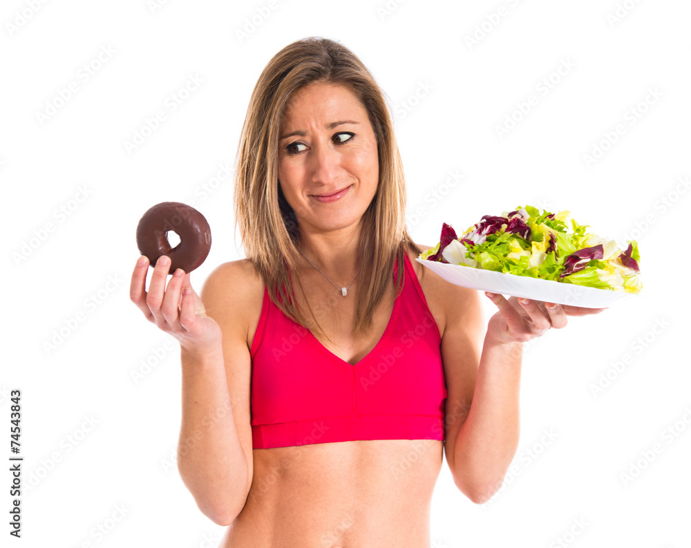 woman undecided between a donut and a salad