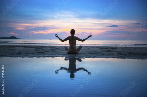 Yoga woman meditating on the ocean beach. Yoga and fitness.