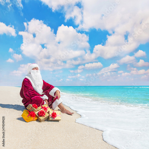 Santa Claus with many christmas golden gifts relaxing on tropica
