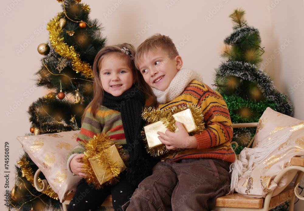 Sister and brother having fun under golden Christmas tree